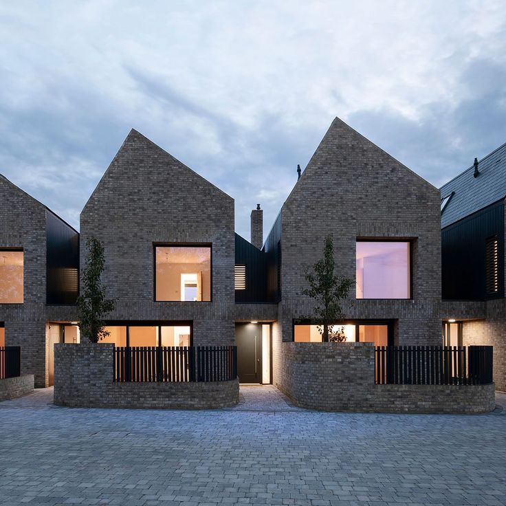 three brick buildings with windows and balconies at dusk