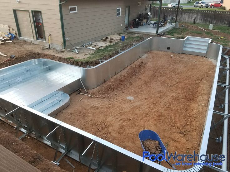 an above ground swimming pool being built in a backyard with dirt and grass around it