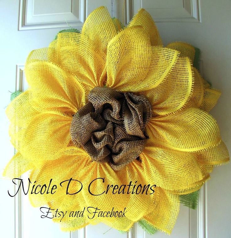 a yellow sunflower is hanging on the front door with burlap and mesh