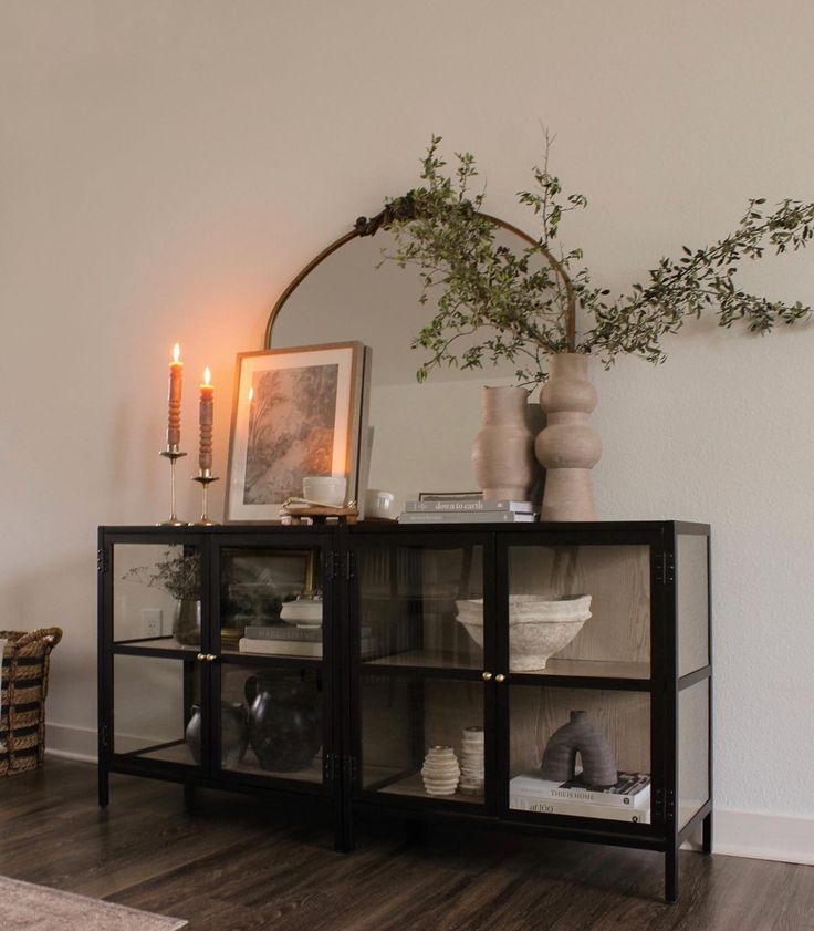 a mirror and some vases on top of a shelf in a room with wood floors