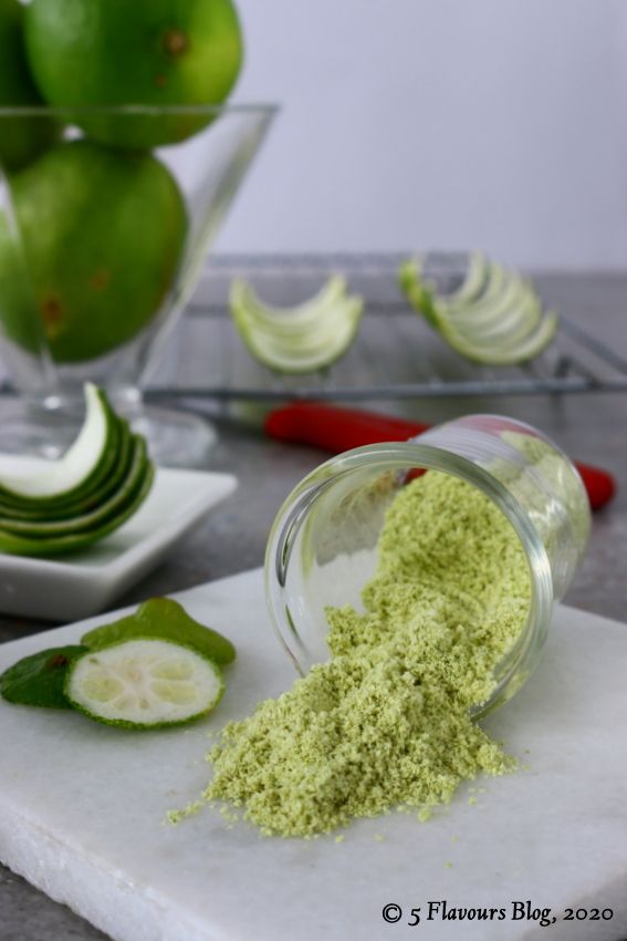 a glass bowl filled with green powder next to sliced limes and cucumbers