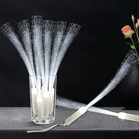 a vase filled with lots of white candles next to utensils and a knife