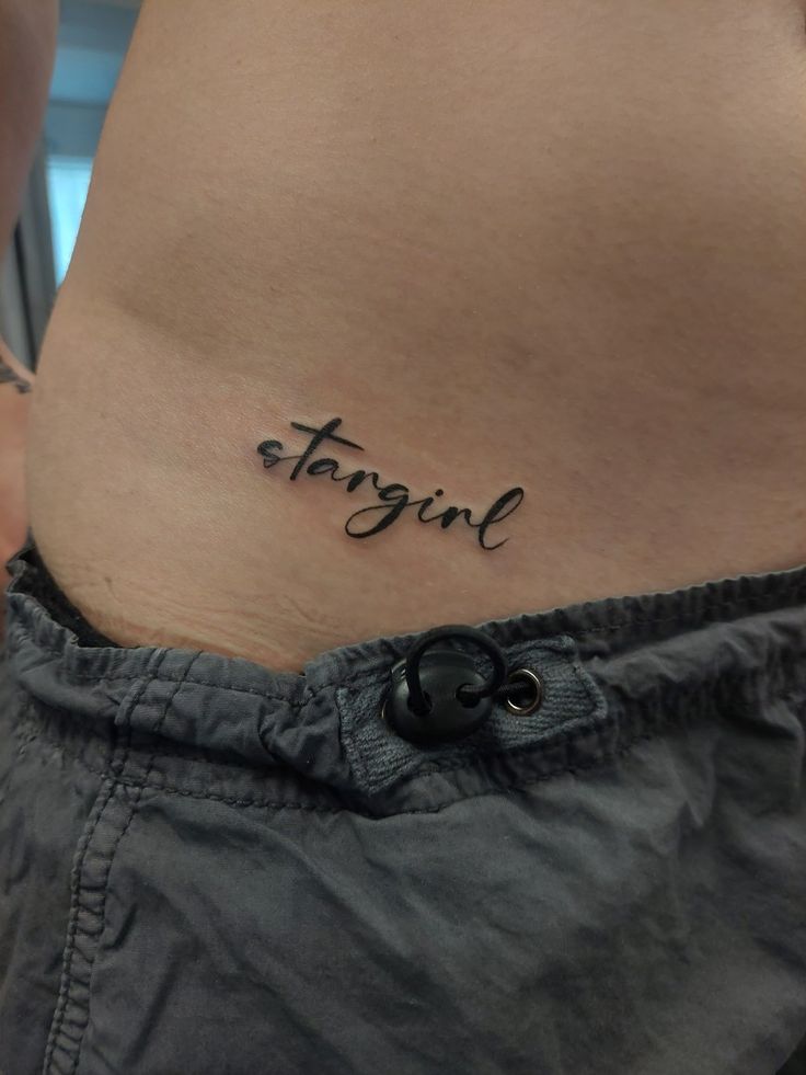 a woman's stomach with the word tattoo on her belly and an inscription in cursive writing