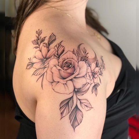 a woman with a flower tattoo on her shoulder and chest is sitting in a chair