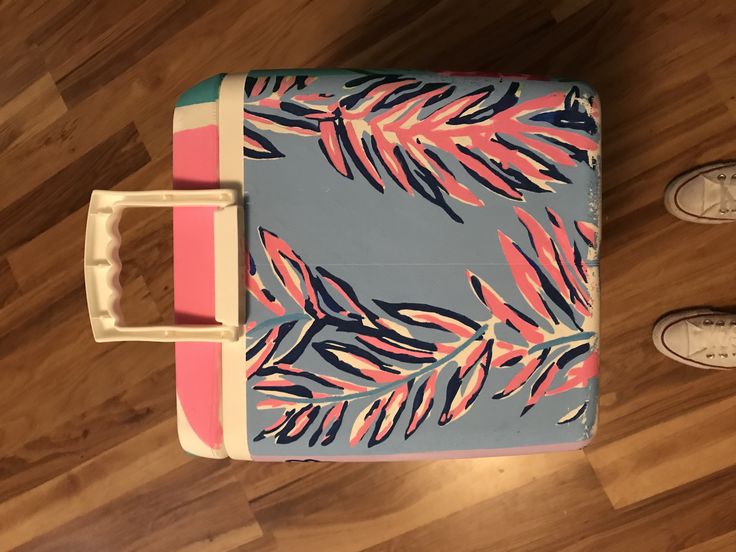 a blue and pink suitcase sitting on top of a wooden floor next to someone's feet