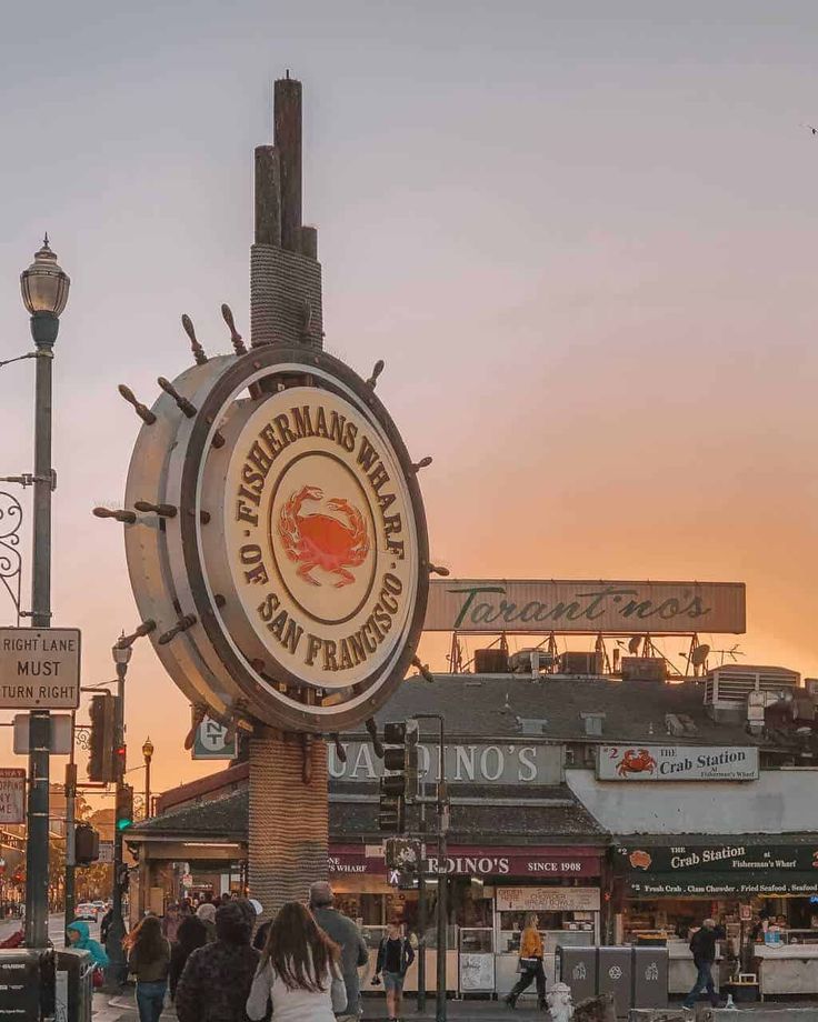 people are walking on the sidewalk in front of a seafood restaurant and bar at sunset