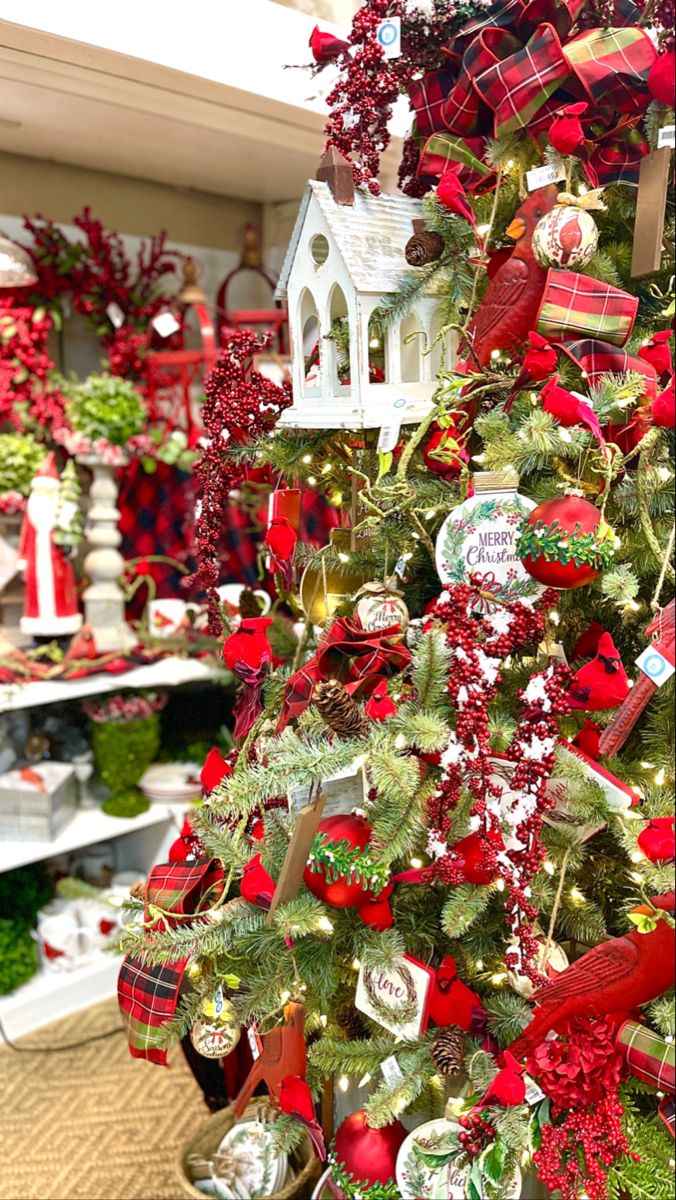 a christmas tree with red and green ornaments on it in a store window display area