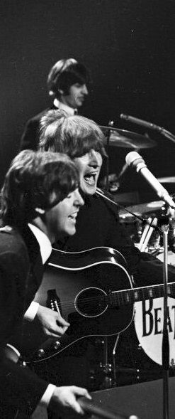 the beatles performing on stage in front of microphones