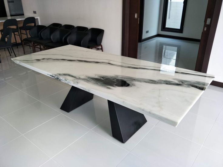 a white marble table with black legs in a room filled with chairs and other furniture