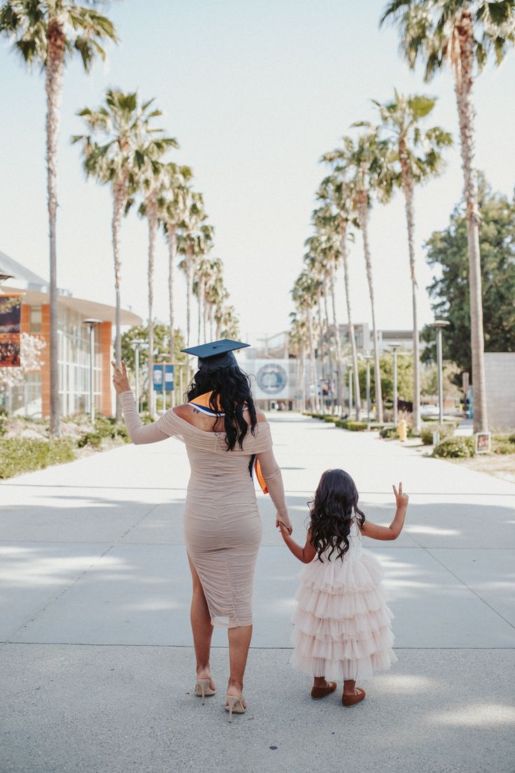 a mother and daughter walking down the street holding hands with palm trees in the background