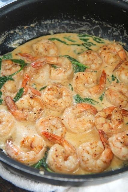 a skillet filled with shrimp and sauce on top of a table