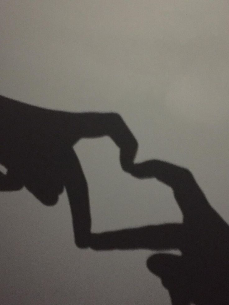 the shadow of two hands holding each other's hand in front of a gray sky