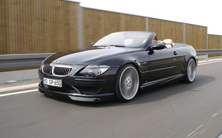 a black convertible car driving down the road