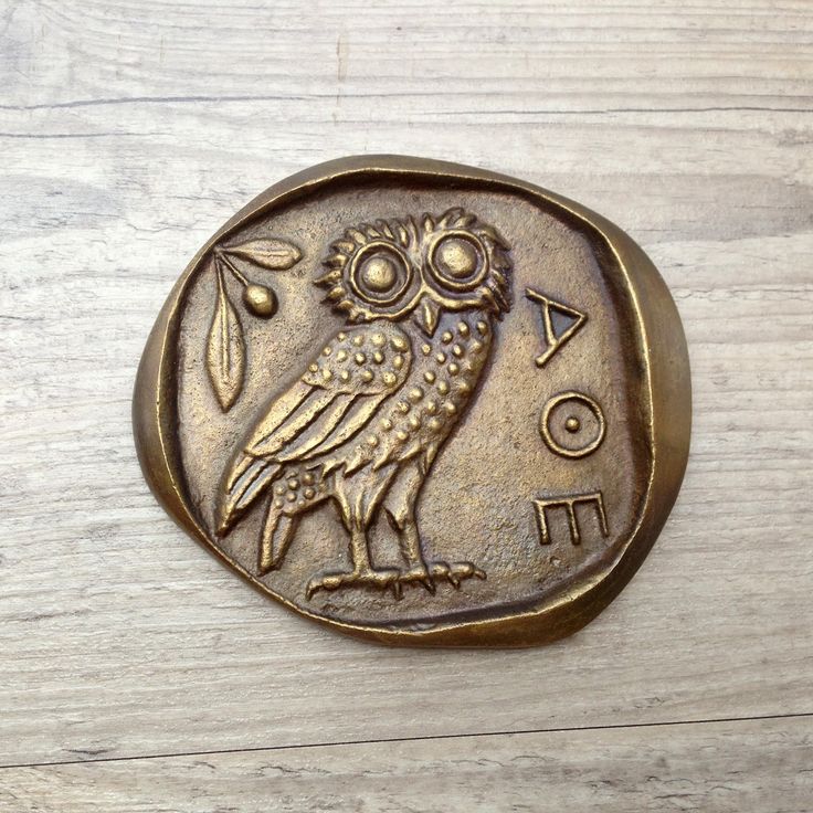 an owl is sitting on the side of a coin that has been placed on a table