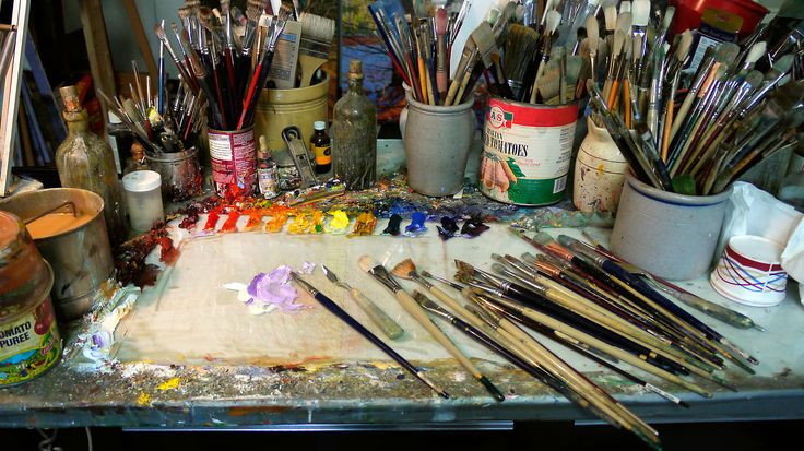 many paint brushes and other art supplies on a table