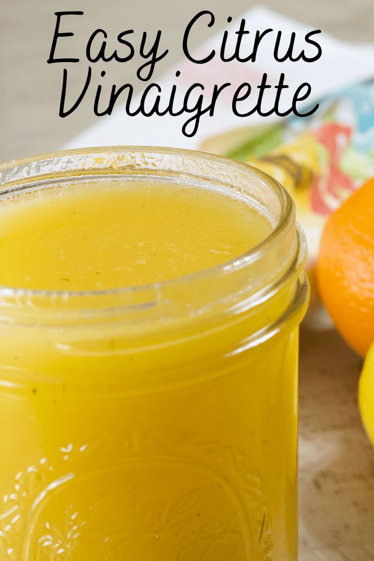 a jar filled with yellow liquid next to oranges