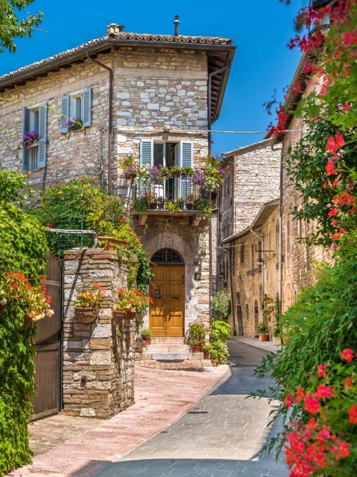 an old stone building with flowers growing on it's windows and balconies