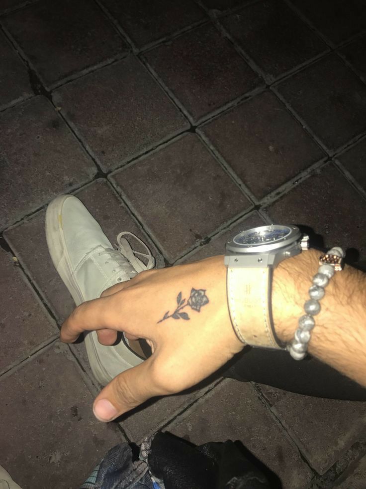 a person with a tattoo on their wrist holding onto a drink in the other hand