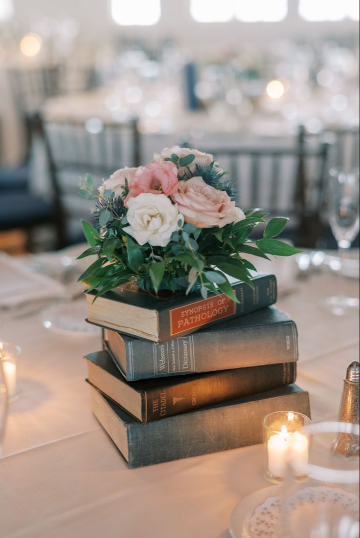 three books stacked on top of each other at a table with candles in the background