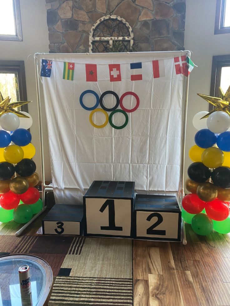 an olympic themed party with balloons and streamers in the shape of numbers on blocks