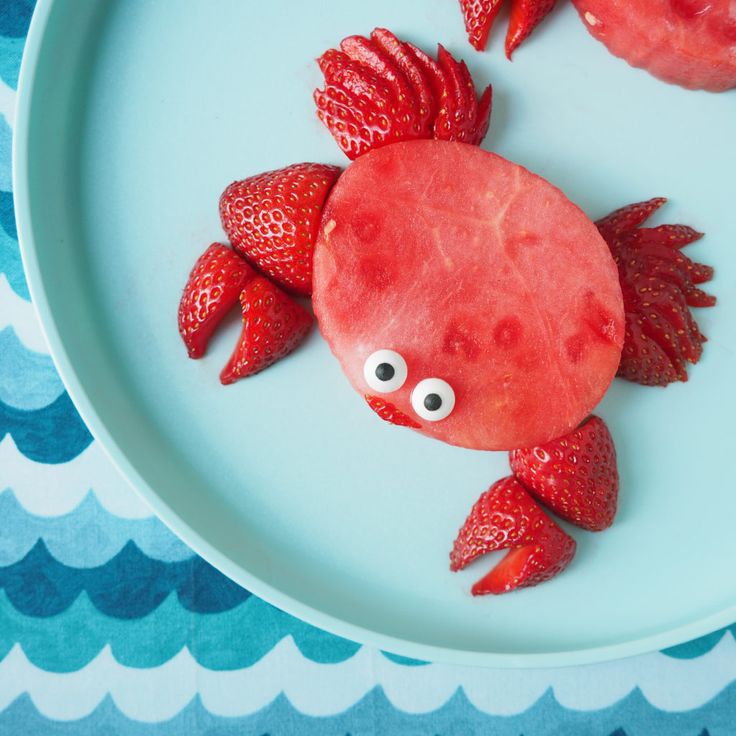 a plate that has some strawberries on it and a crab made out of watermelon