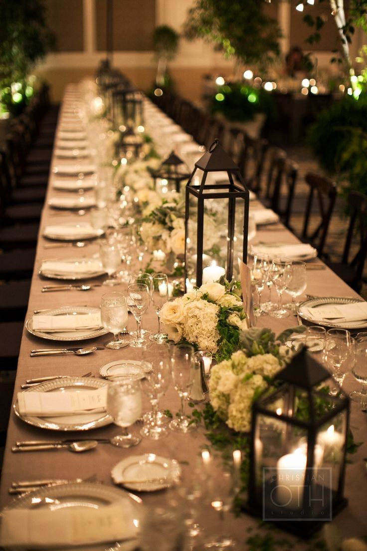 a long table is set with white flowers and candles for an elegant dinnereon party