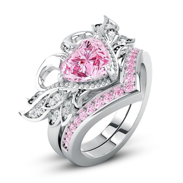 a pink heart shaped ring with diamonds on the sides and an intricate design around it