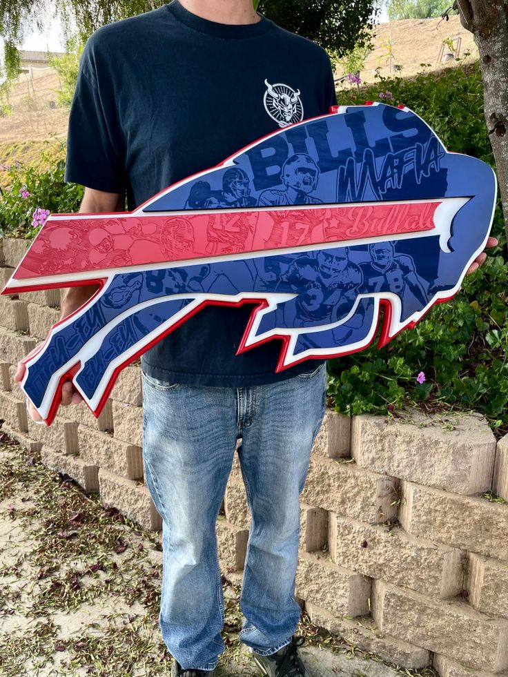 a man is holding up a skateboard shaped like an eagle with red, white and blue designs on it