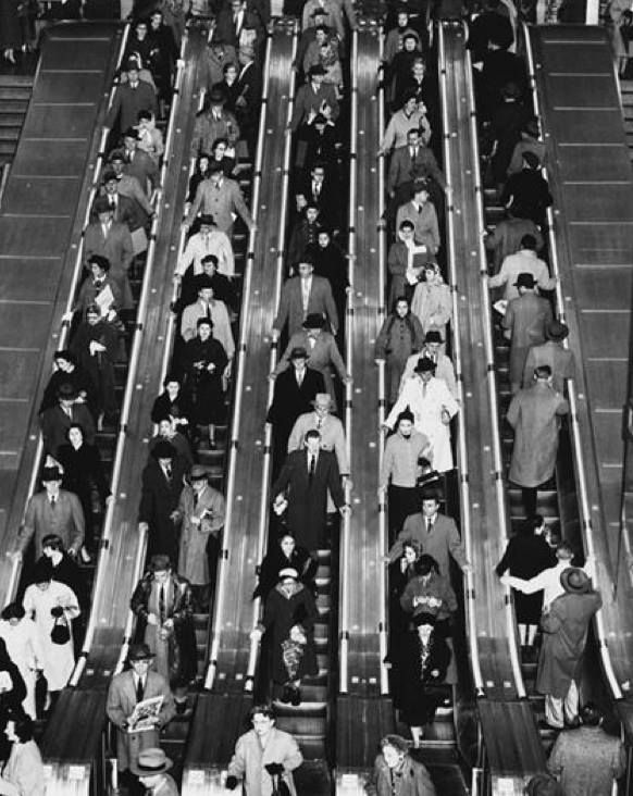 an old black and white photo of people on escalators