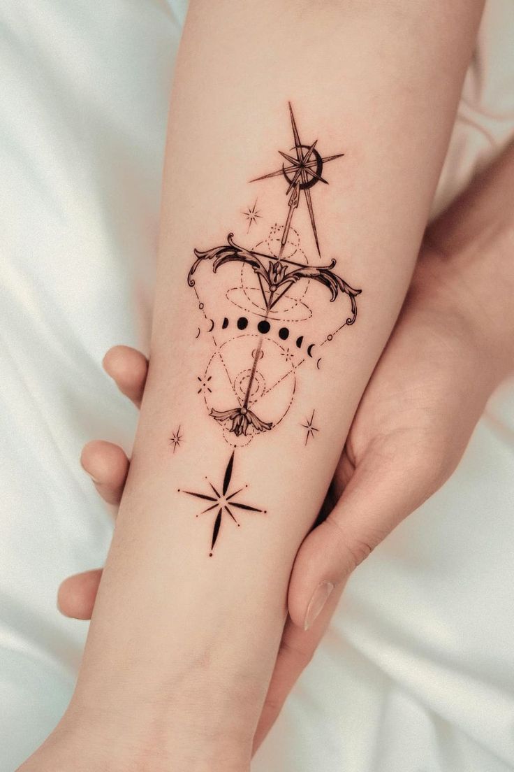 a woman's arm with a tattoo on it that has an arrow and stars