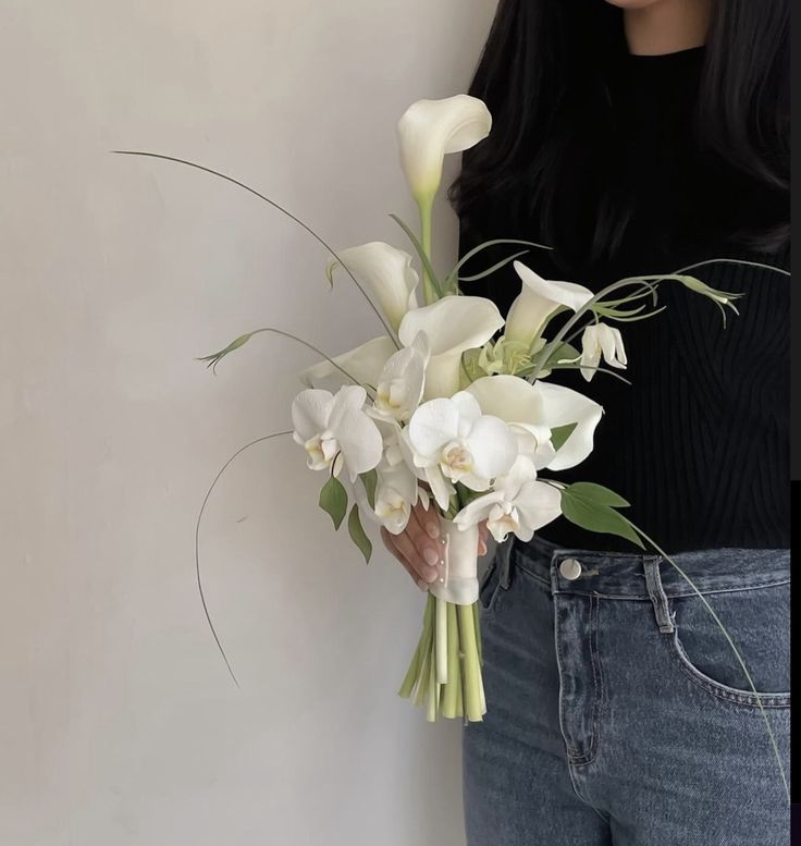 a woman holding a bouquet of white flowers