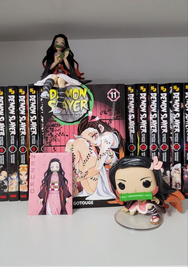 a collection of action figures and books on a table with an anime character figurine next to them