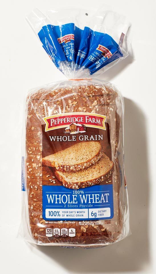 a loaf of whole grain bread sitting on top of a white table next to a bag of pepperidge farm whole grain bread