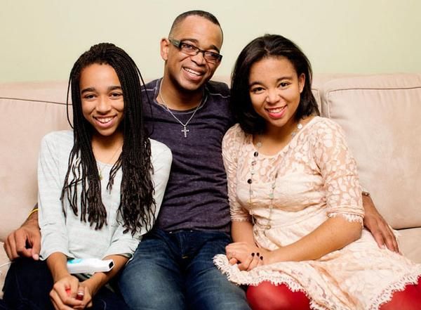 three people sitting on a couch smiling at the camera