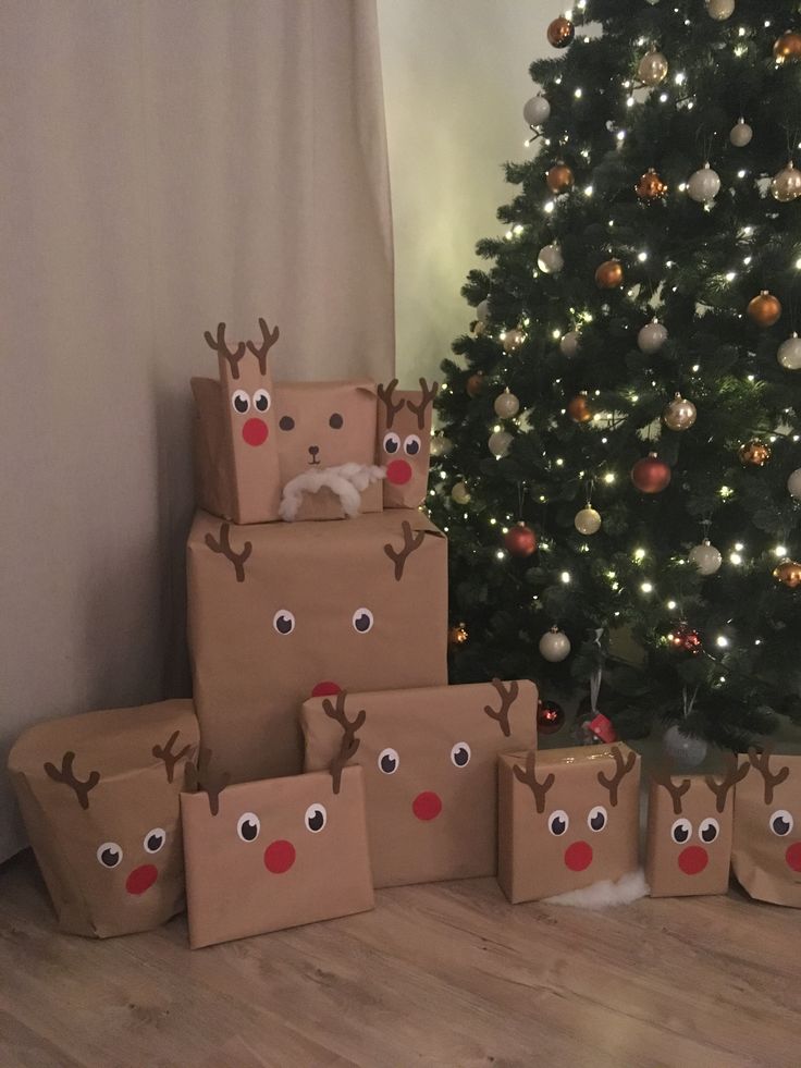 some brown boxes with reindeer faces on them and a christmas tree in the back ground