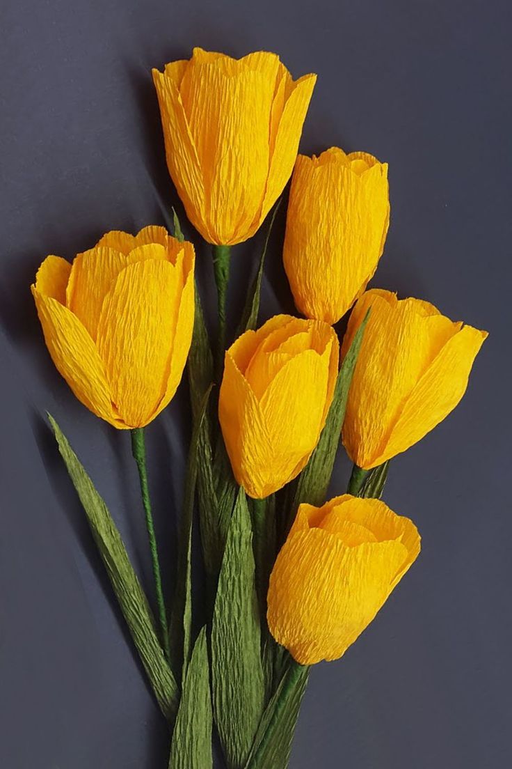 yellow flowers are arranged on a gray surface