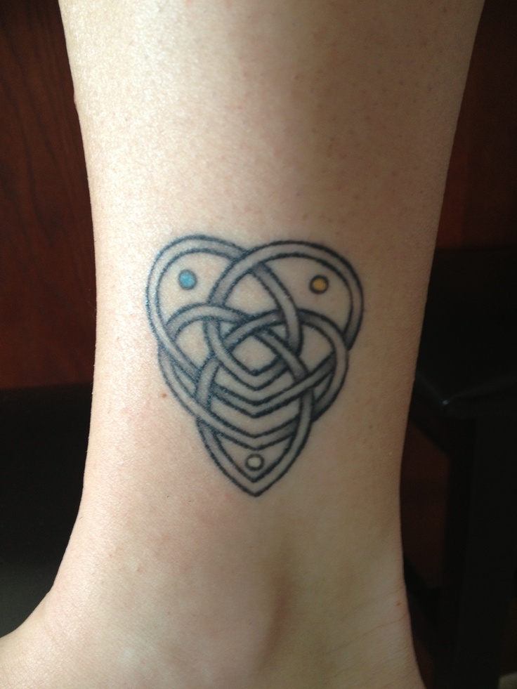 a small tattoo on the foot of a woman's ankle, depicting an intertwined heart