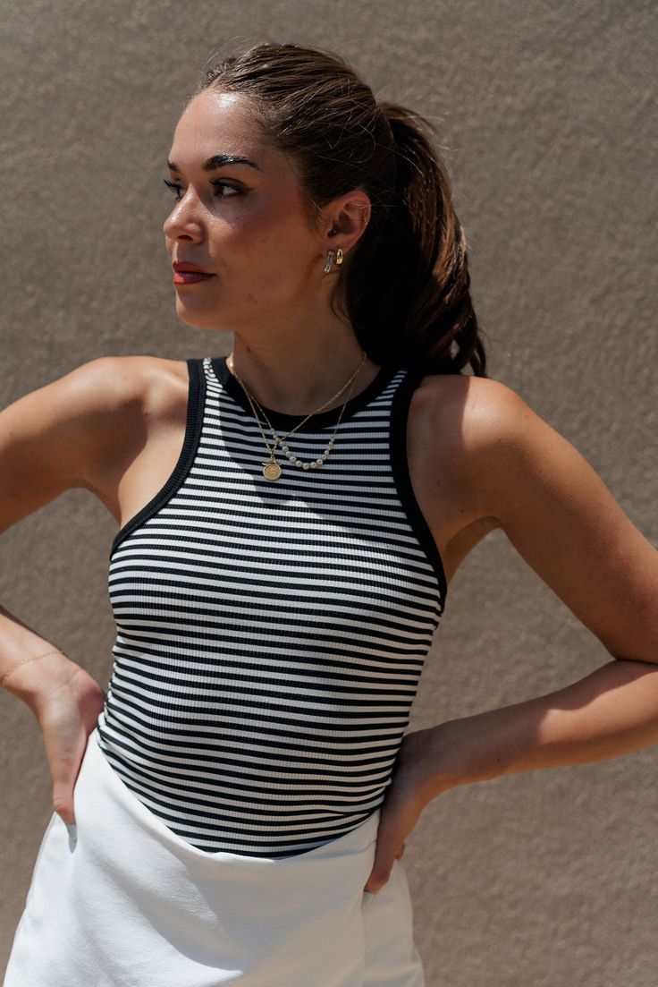 close up view of female model wearing the Selene Black & White Stripe Tank which features Black and White Stripe Pattern, Black Trim Details, Round Neckline and Sleeveless Striped Ribbed Tank Top, Fitted Black Top With Vertical Stripes, Spring Sleeveless Tank Top With Contrast Stripes, Fitted Striped Tank Top, Fitted Tank Top With Contrast Stripes For Spring, Black Tops With Striped Collar For Summer, Black Summer Top With Striped Hem, Black Summer Top With Vertical Stripes, Black Summer Tops With Striped Hem