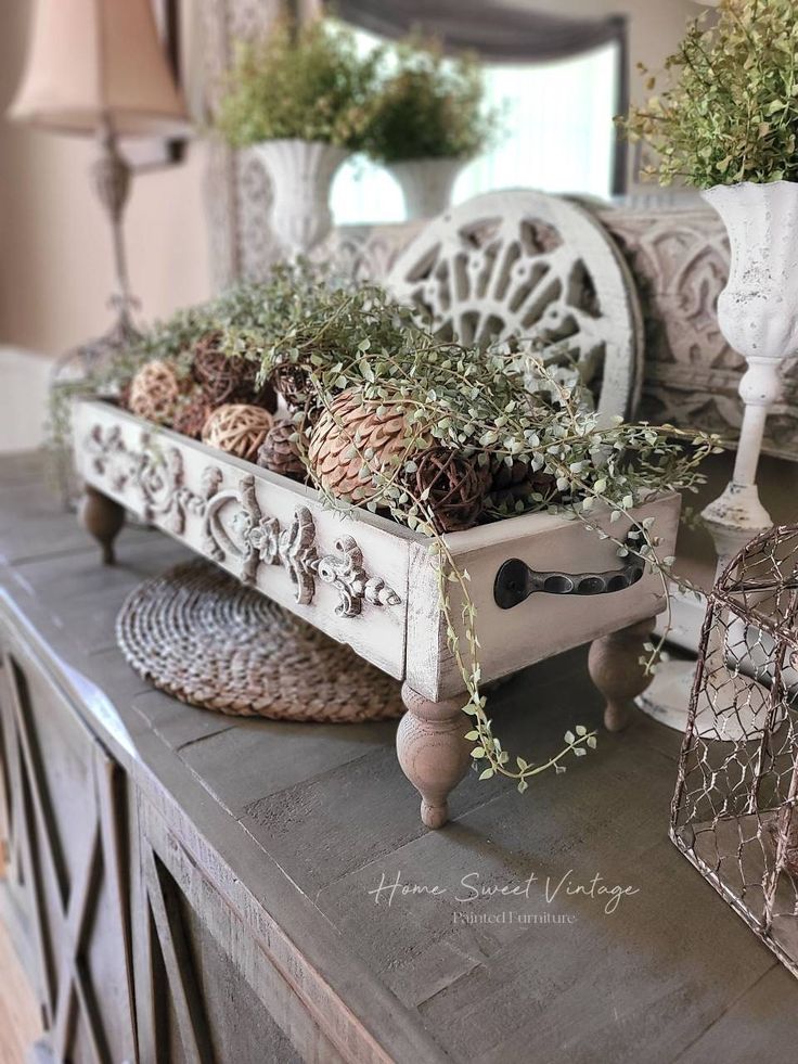 a table topped with lots of plants on top of a wooden table next to a mirror