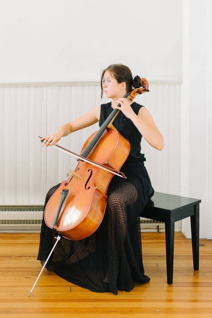 a woman in a black dress is playing the cello