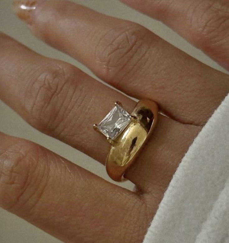 a close up of a person's hand wearing a gold ring with a diamond