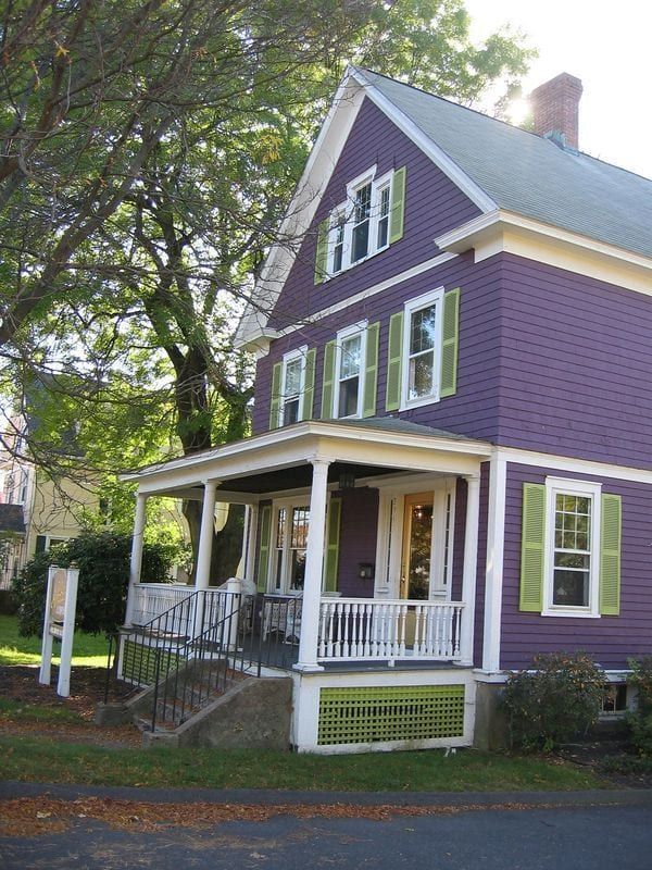 a purple house with white trim and green shutters on the front porch is shown