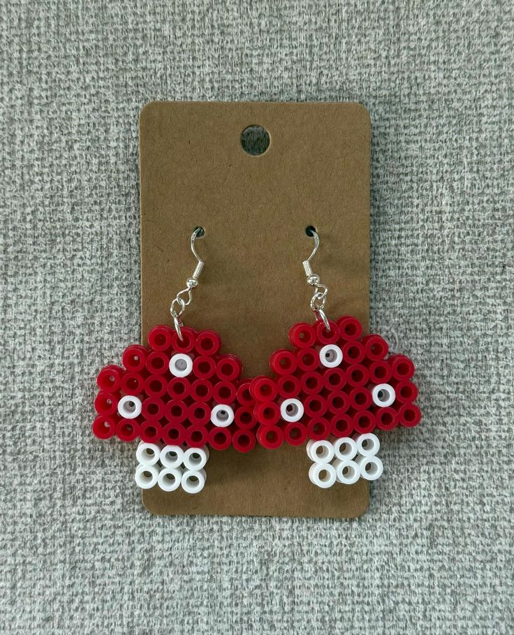 the earrings are made out of legos and have red flowers on them, with white dots