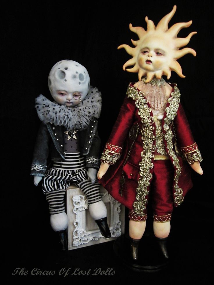 two figurines sitting next to each other in front of a black background,