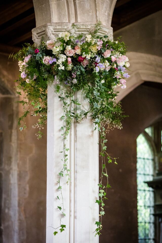 an old pillar with flowers and greenery hanging from it