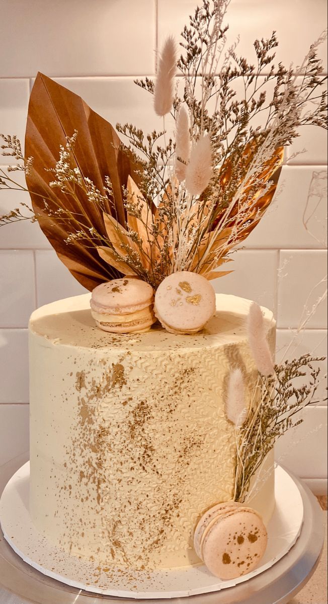 a white cake with frosting and dried flowers on top