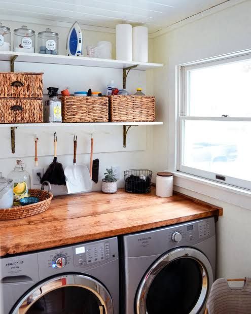 a washer and dryer in a small room with open shelving on the wall