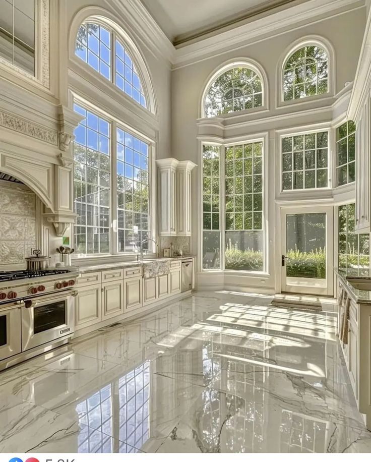 a large kitchen with marble counter tops and white cabinets, along with an arched window