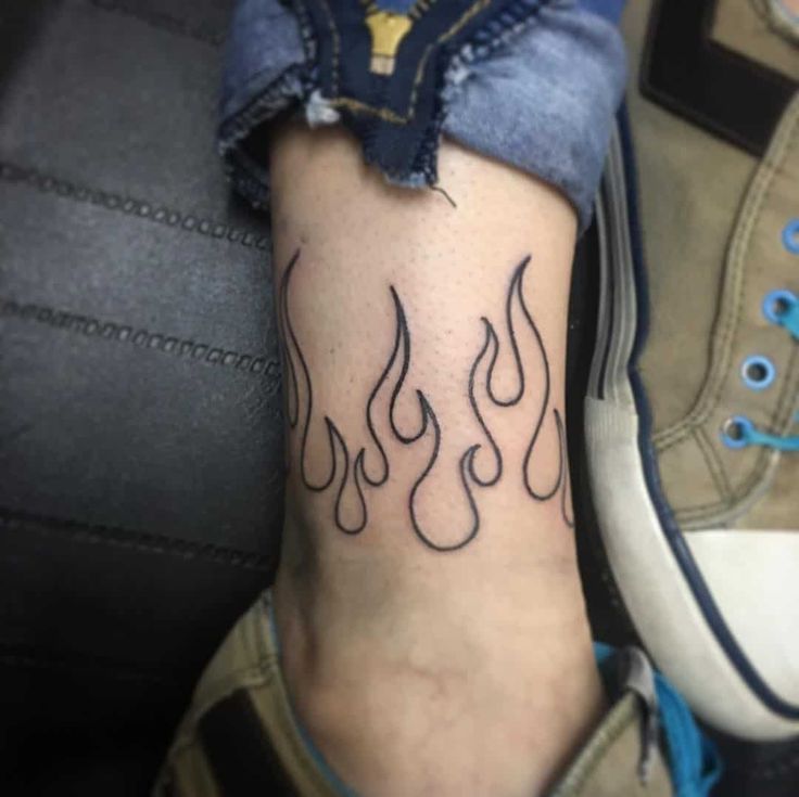 a person with a tattoo on their foot that has flames coming out of the bottom