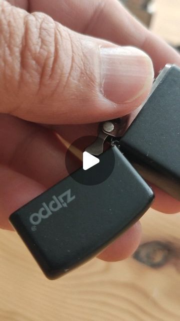 a person holding two small black lighters in their left hand, with the word zipp written on them